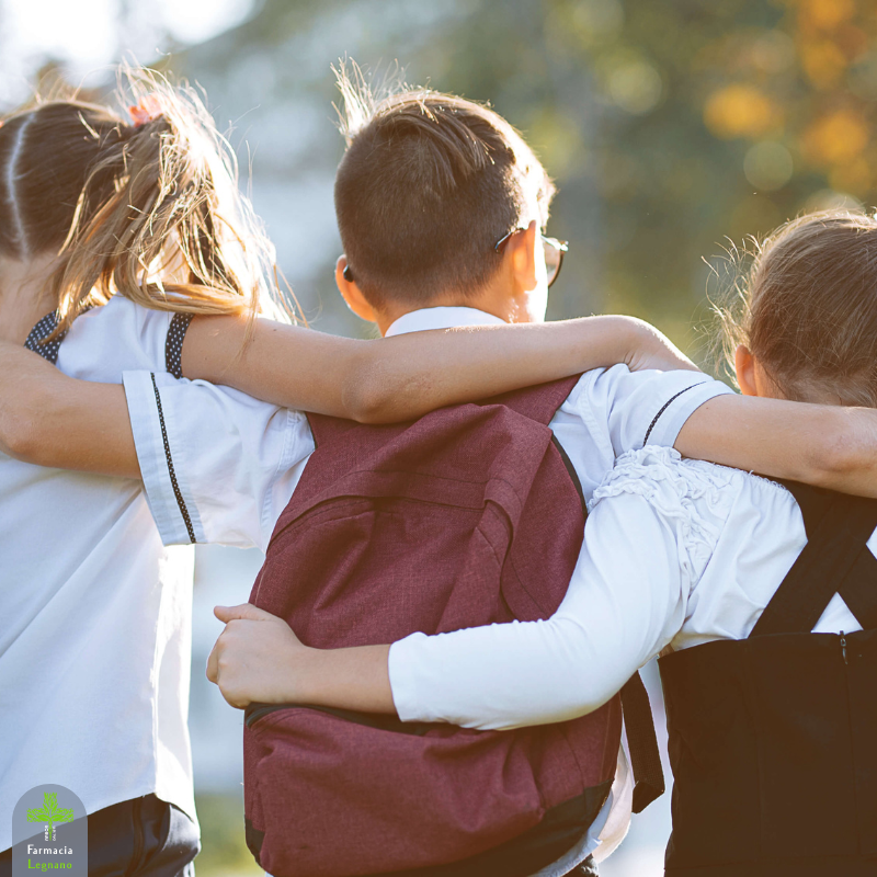 Tre bambini con lo zaino in spalla si stanno abbracciando e stanno andando a scuola. Il rientro a scuola necessita delle giuste attenzioni.