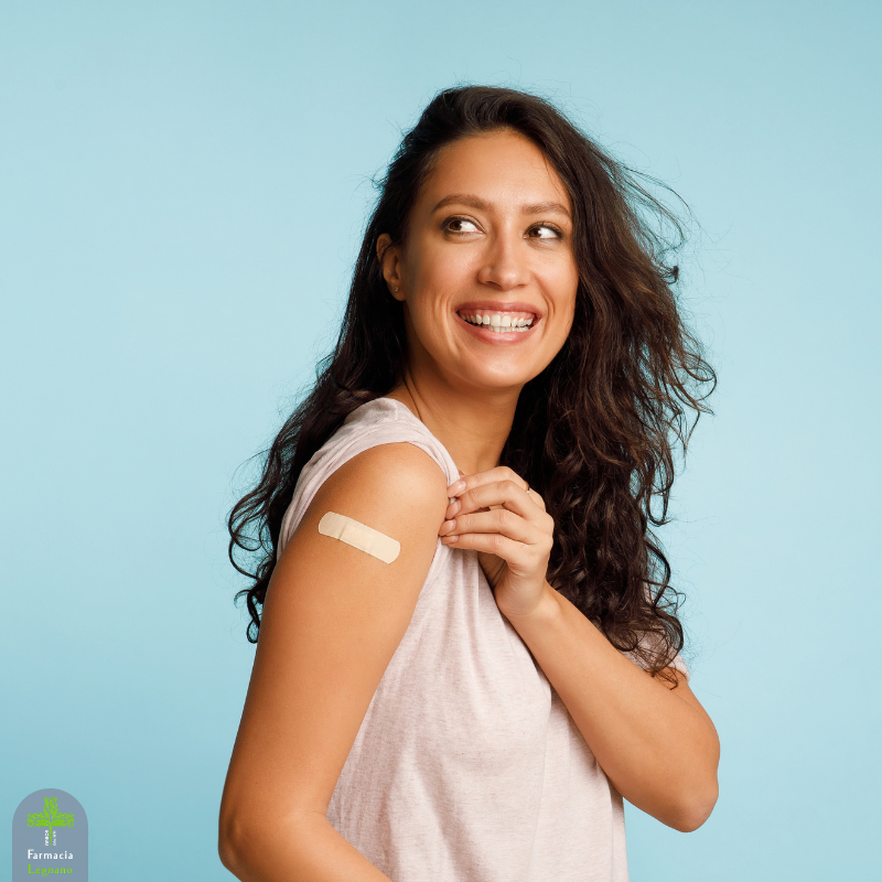 Donna sorridente con cerotto sul braccio dopo una vaccinazione anti-influenzale, immagine dedicata alla campagna di vaccinazione antinfluenzale in farmacia.