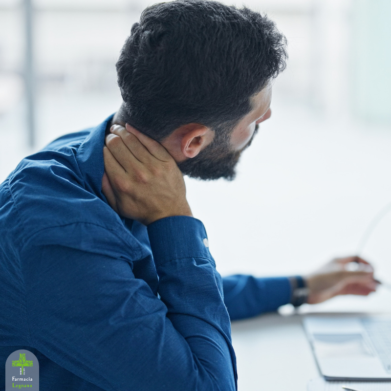 Uomo al computer che si massaggia il collo per un fastidio cervicale, immagine dedicata a tensione e rigidità con l’arrivo dei primi freddi.